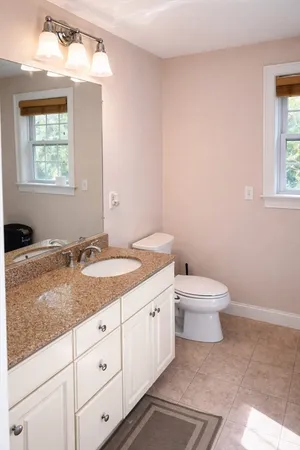 a bathroom with a granite countertop sink mirror and toilet