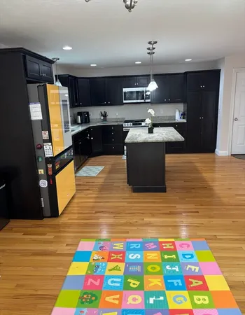 a large room with kitchen island stainless steel appliances wooden floor and cabinets