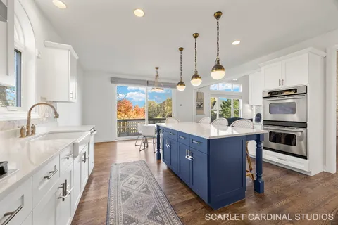 a kitchen with stainless steel appliances granite countertop a sink a stove and a wooden floor