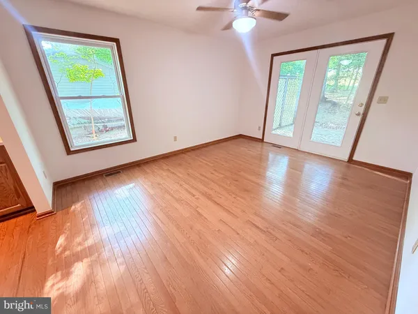 a view of an empty room with wooden floor and a window