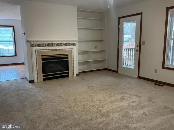 an empty room with a fireplace cabinet and windows