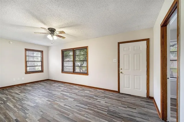 a view of an empty room with a window and wooden floor