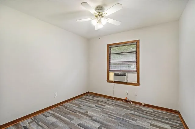 a view of an empty room with window and a chandelier fan