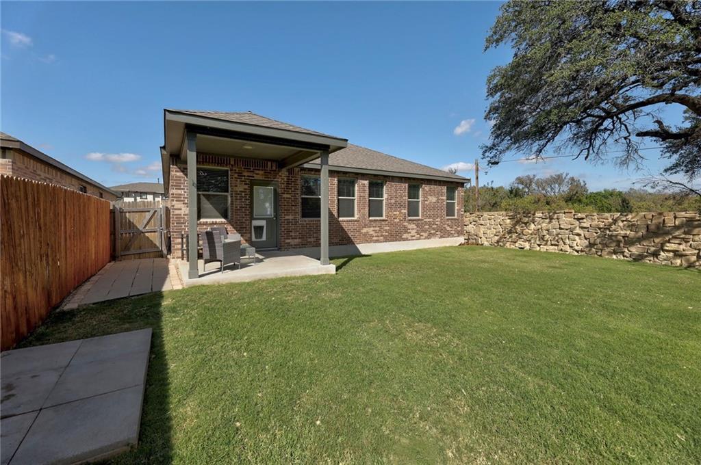 204 Tulum Terrace Leander, TX 78641 - Photo 19 of 22 Back of property featuring a gate, brick siding, a patio area, a fenced backyard, and roof with shingles
