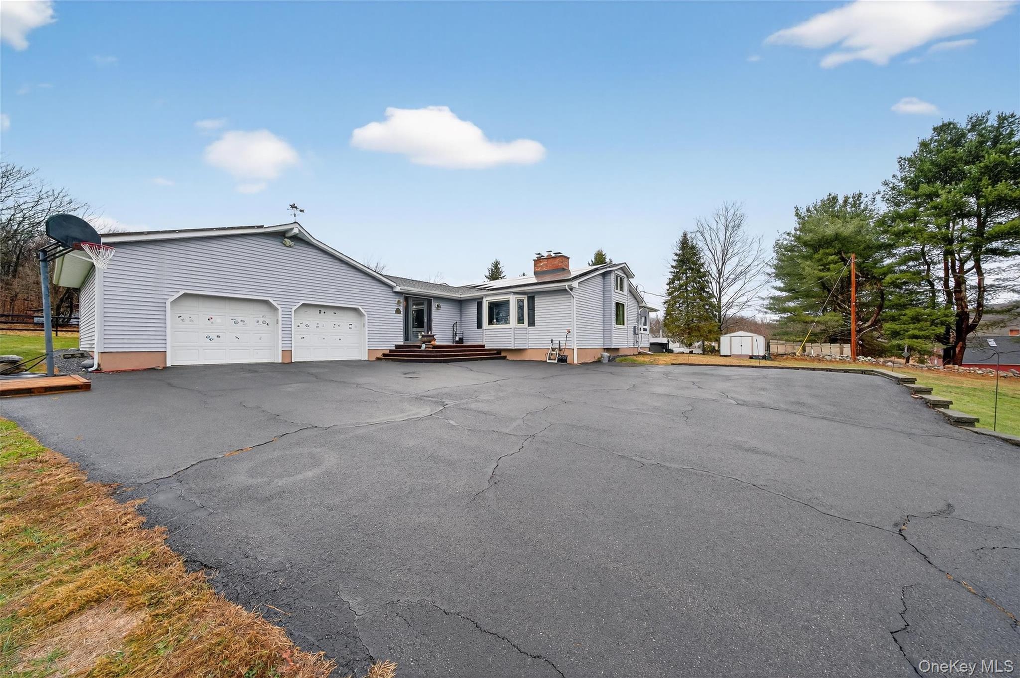 View of front of house with asphalt driveway, an attached garage, and a chimney