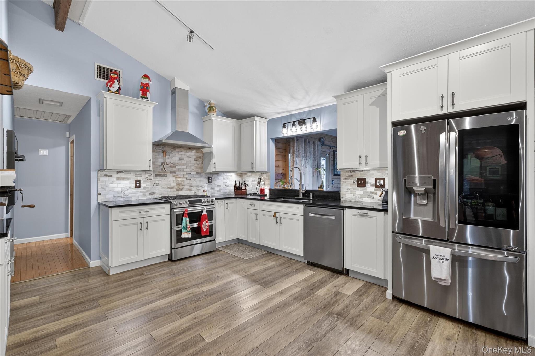 65 Bailey Road New Hampton, NY 10958 - Photo 13 of 50 Kitchen featuring appliances with stainless steel finishes, white cabinets, wall chimney exhaust hood, lofted ceiling, and light wood finished floors