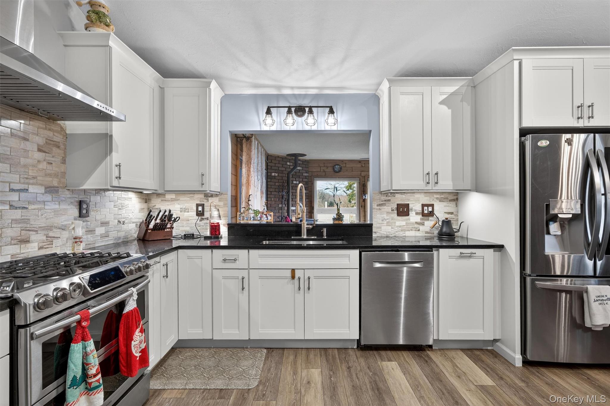 65 Bailey Road New Hampton, NY 10958 - Photo 15 of 50 Kitchen with stainless steel appliances, wall chimney exhaust hood, white cabinets, dark stone countertops, and light wood-style flooring