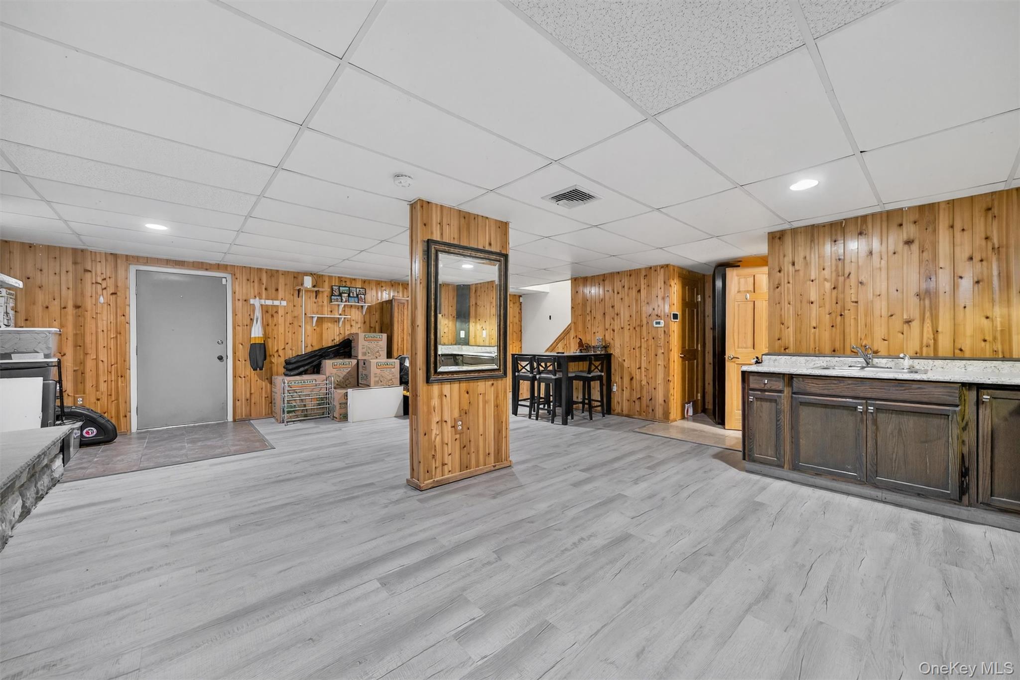 65 Bailey Road New Hampton, NY 10958 - Photo 39 of 50 Bar area with wooden walls, light wood-style floors, dark brown cabinetry, and a paneled ceiling