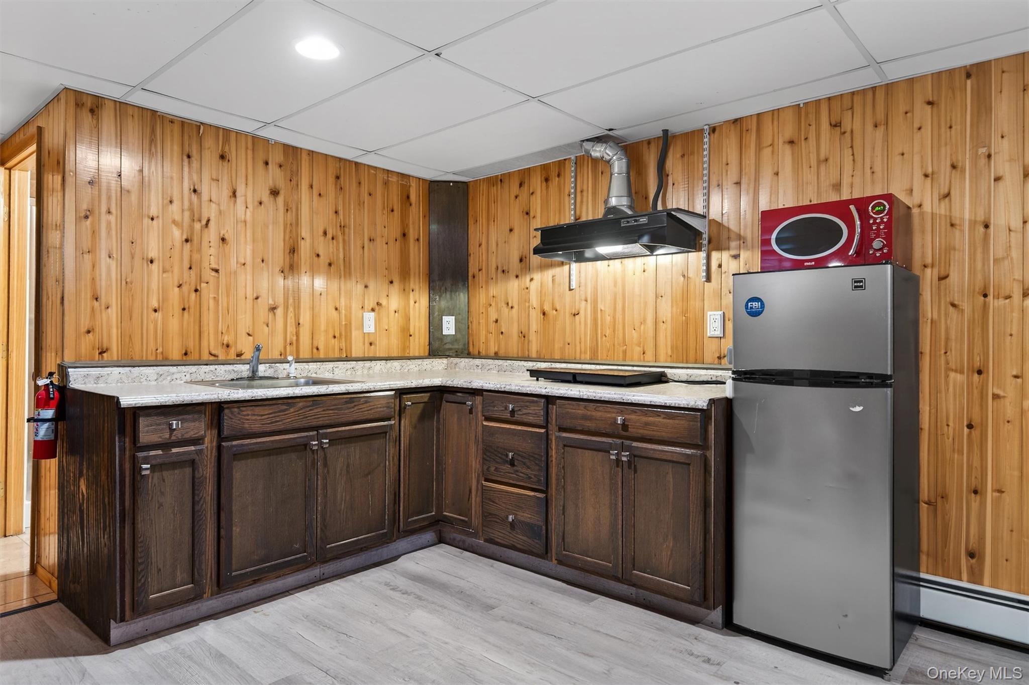 65 Bailey Road New Hampton, NY 10958 - Photo 41 of 50 Kitchen featuring freestanding refrigerator, dark brown cabinetry, a drop ceiling, range hood, and light wood-style floors