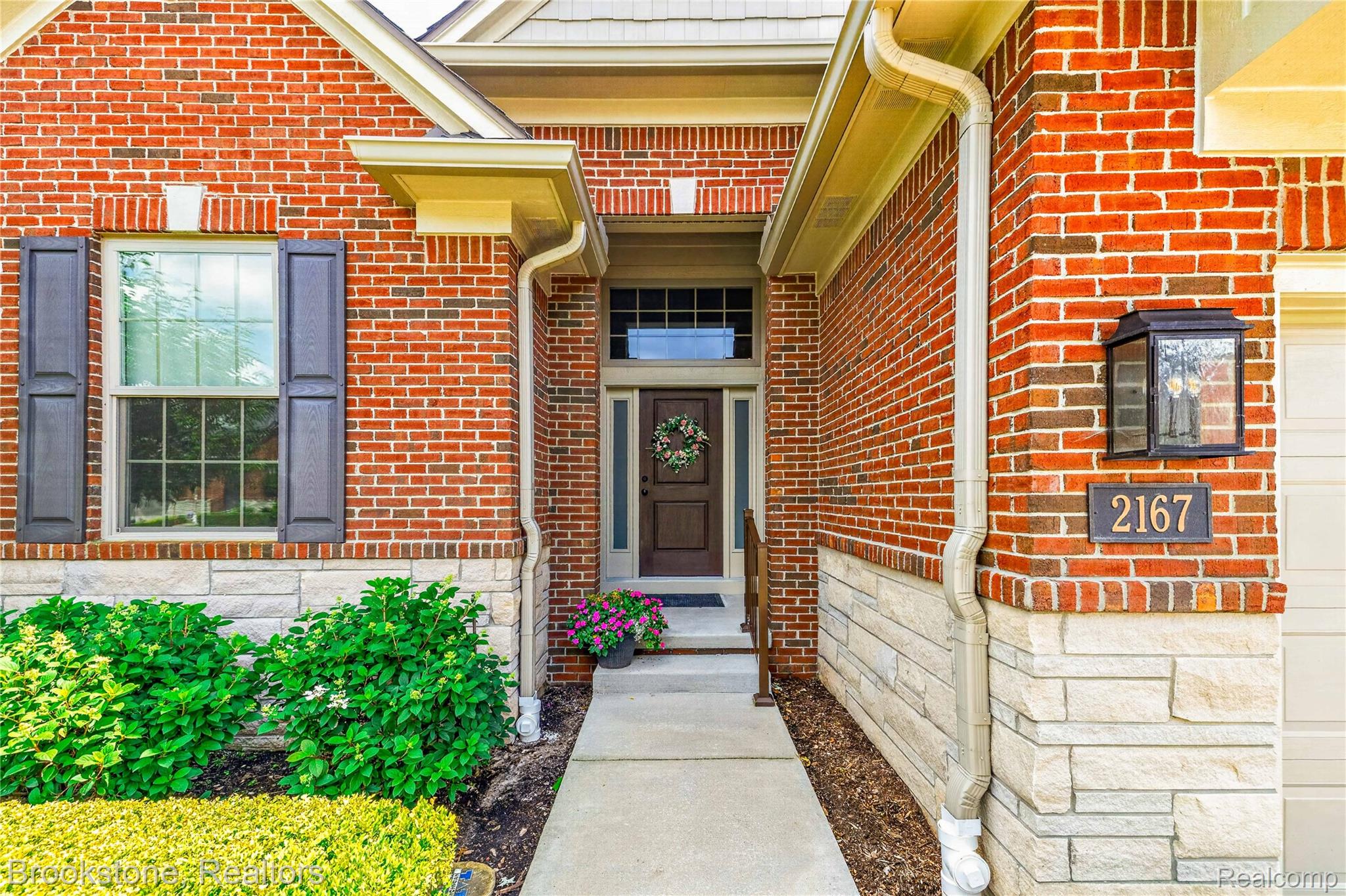 2167 Sanctuary Court Rochester, MI 48309 - Photo 2 of 68 Brick and stone facade featuring a front entry with transom window, dark wood door, and a concrete pathway