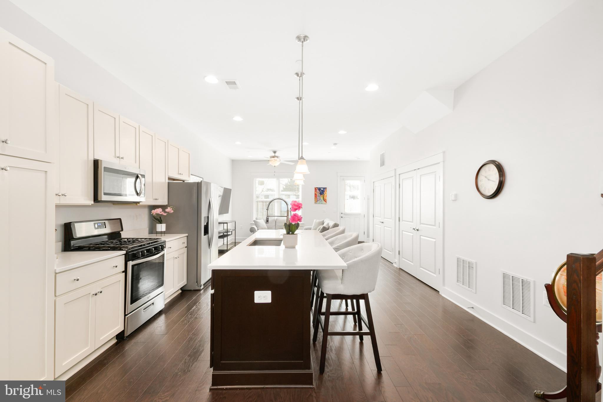 224 East 6th Street Frederick, MD 21701 - Photo 14 of 55 a kitchen with stainless steel appliances kitchen island granite countertop a sink stove and white cabinets with wooden floor