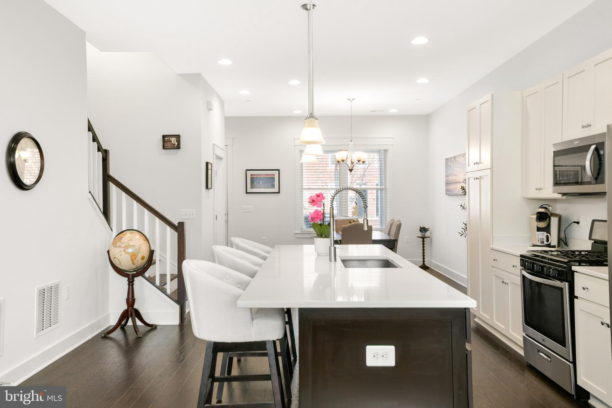 224 East 6th Street Frederick, MD 21701 - Photo 19 of 55 a kitchen with stainless steel appliances kitchen island granite countertop a stove a sink a microwave a dining table and chairs with wooden floor