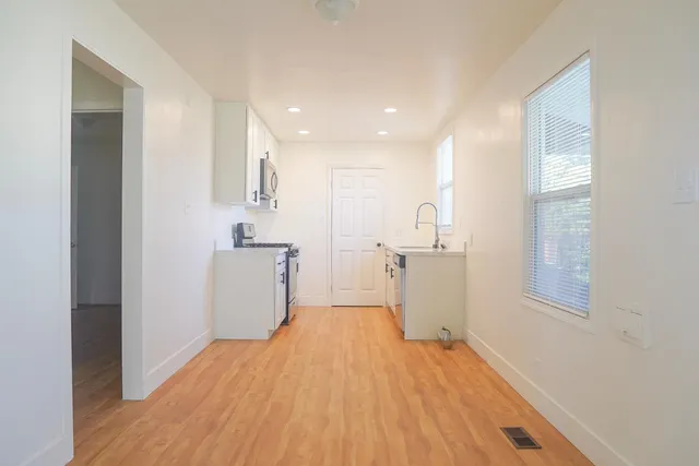 a view of a kitchen with wooden floor and white cabinets