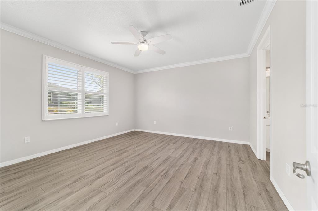 10064 Southwest 88th Street Ocala, FL 34481 - Photo 21 of 47 an empty room with wooden floor chandelier fan and windows