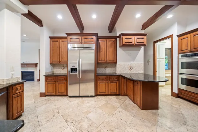 a large kitchen with stainless steel appliances kitchen island granite countertop a refrigerator and a sink