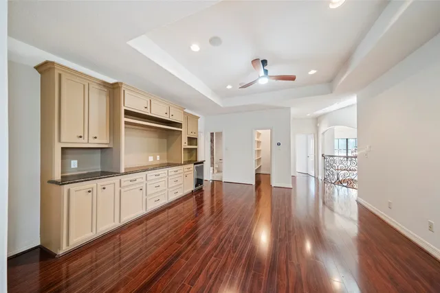 a kitchen with granite countertop a stove top oven a sink dishwasher and white cabinets with wooden floor