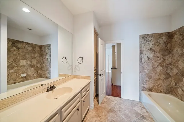 a bathroom with a tub sink and mirror