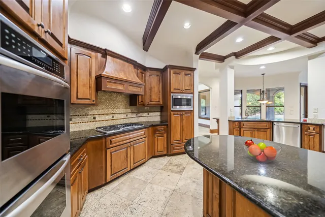 a kitchen with stainless steel appliances granite countertop a sink a stove and a wooden cabinets