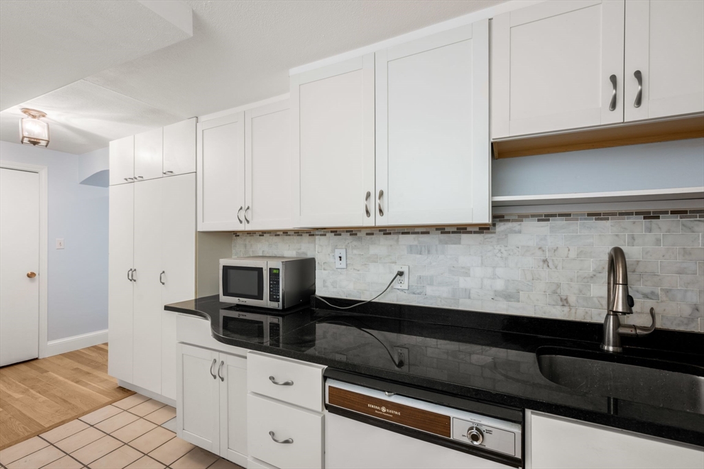 242 Beacon Street, Unit 1 Boston, MA 02116 - Photo 14 of 29 a kitchen with granite countertop white cabinets and black appliances