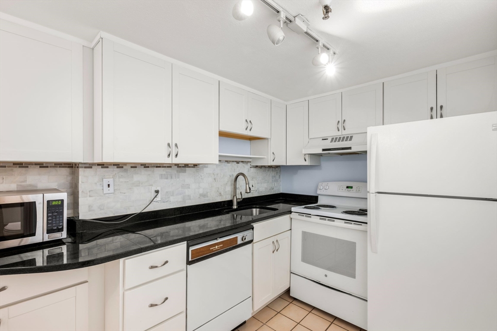 242 Beacon Street, Unit 1 Boston, MA 02116 - Photo 15 of 29 a kitchen with granite countertop white cabinets and white appliances