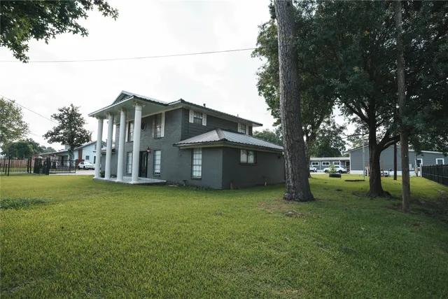 a view of a house with a big yard and large trees