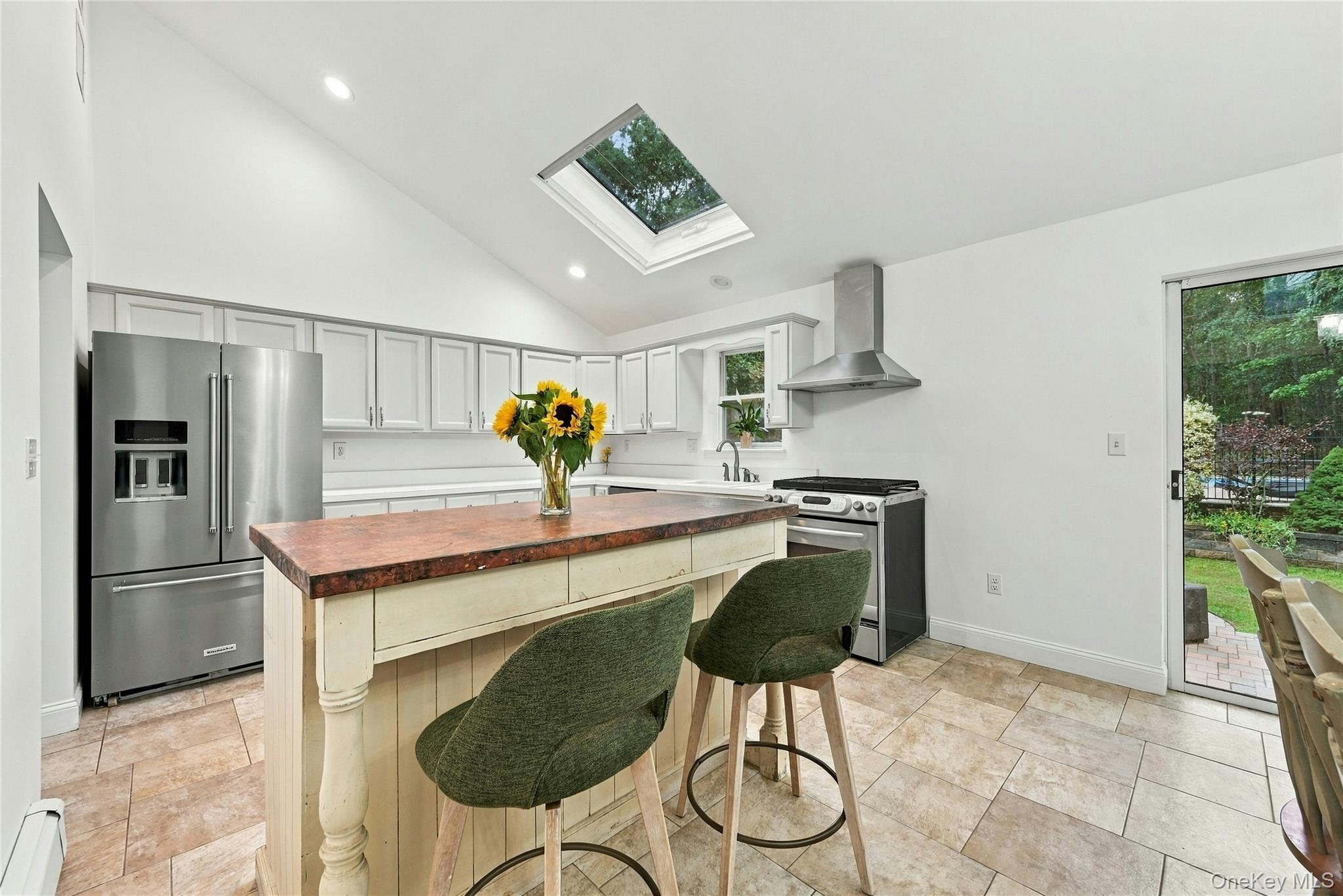 16 Georgann Road Manorville, NY 11949 - Photo 10 of 32 Vaulted ceiling with skylight, stainless steel appliances, light-toned cabinetry, island with countertop, and tile flooring