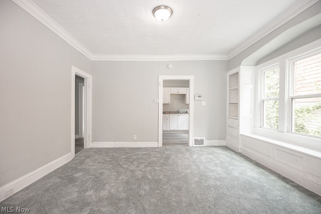 1000 Eddy Road Cleveland, OH 44108 - Photo 7 of 38 Spare room featuring light carpet, crown molding, and a textured ceiling