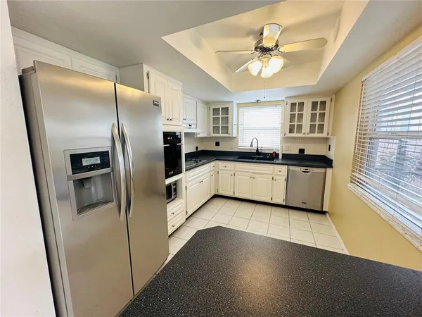 a kitchen with granite countertop a sink a refrigerator a stove and cabinets