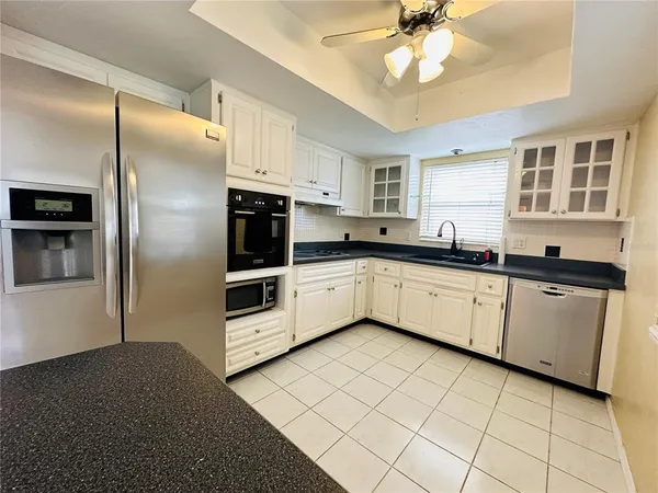 a kitchen with stainless steel appliances a sink a stove a refrigerator cabinets and a window