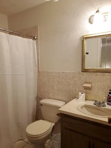 a bathroom with a sink a toilet a mirror and shower curtain