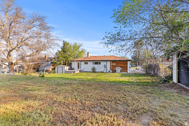 2101 West 3900th Street South Roy, UT 84067 - Photo 5 of 36 Spacious backyard featuring a large grass area, mature trees, and a detached storage shed