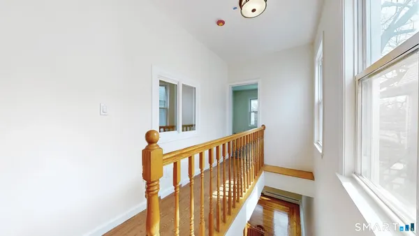 a view of staircase with lots of frames on wall and a large window
