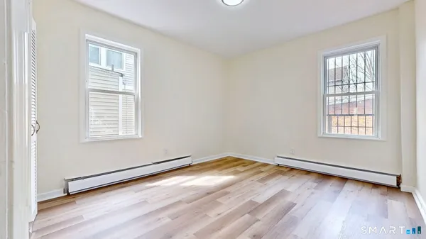 an empty room with wooden floor and windows