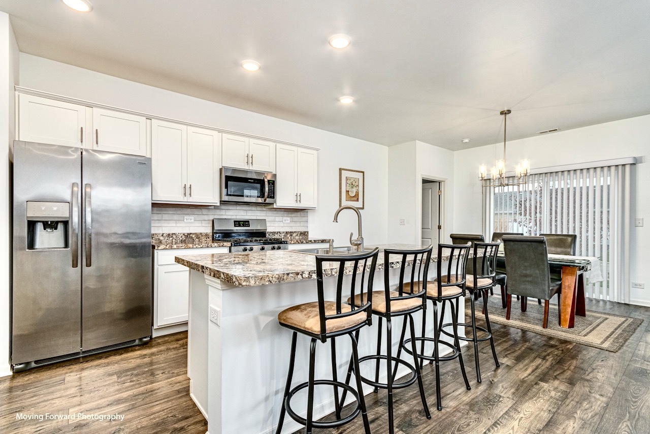 1908 Southern Circle, Unit 1908 Pingree Grove, IL 60140 - Photo 8 of 30 a kitchen with stainless steel appliances a dining table chairs microwave and refrigerator