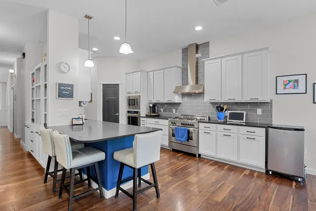 a kitchen with white cabinets and chairs
