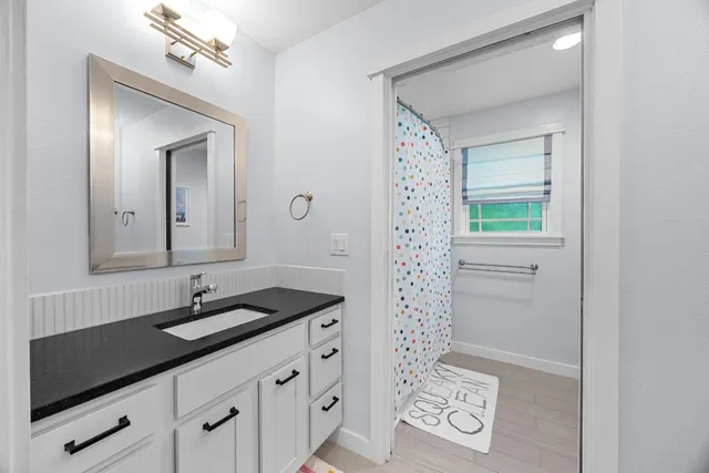 a bathroom with a granite countertop sink a mirror and a shower