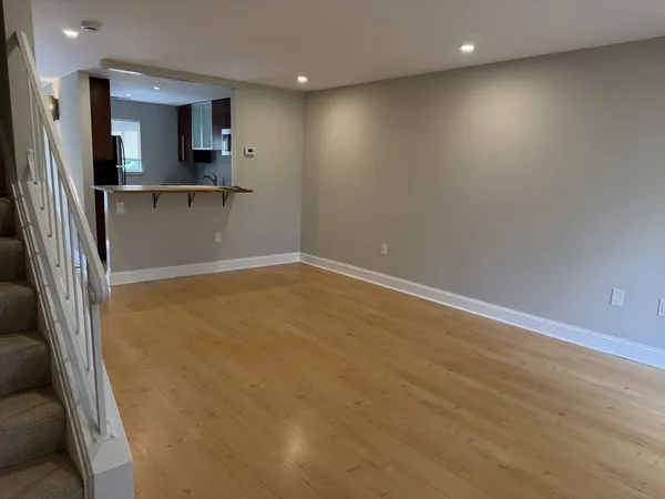 an empty room with kitchen view and a fireplace