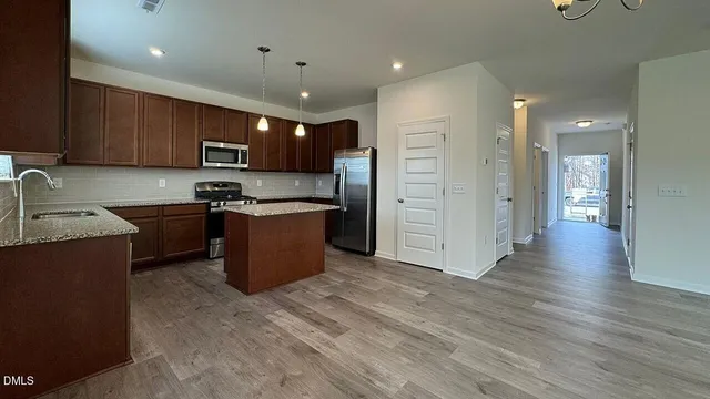 a kitchen with kitchen island granite countertop wooden floor and refrigerator