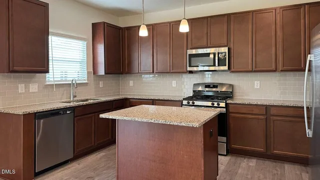 a large kitchen with stainless steel appliances granite countertop a refrigerator and a stove top oven