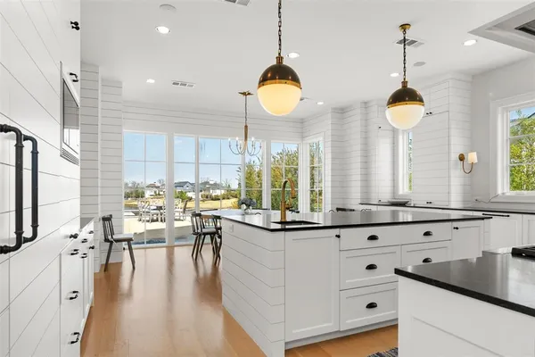 a very nice looking kitchen with granite countertop a stove a sink a dining table and chairs