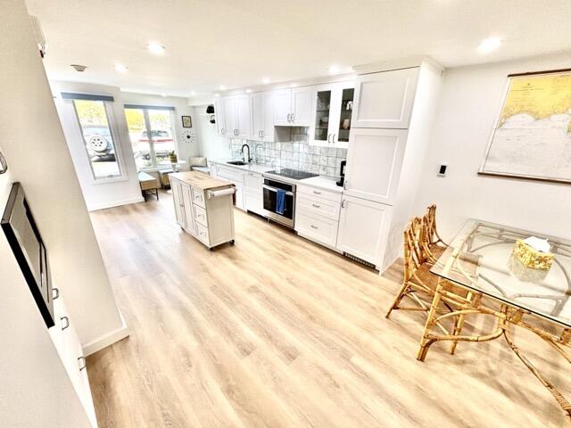 500 Ocean Street, Unit 147 Hyannis, MA 02601 - Photo 4 of 23 a kitchen with a sink dishwasher stove and white cabinets with wooden floor