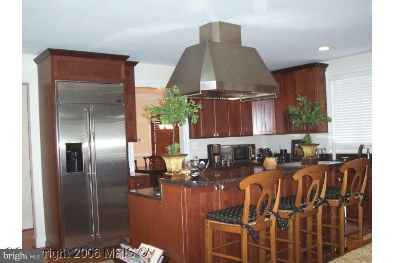 4416 Ridge Street Chevy Chase, MD 20815 - Photo 8 of 20 a kitchen with granite countertop a refrigerator a stove a sink and a dining table with wooden floor