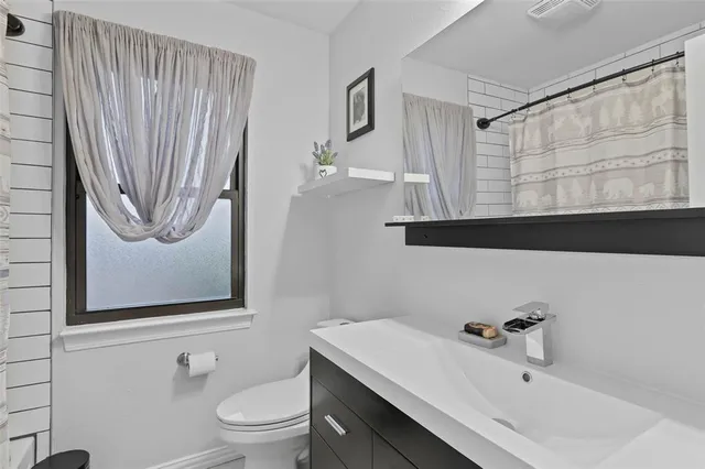 a bathroom with a sink a toilet and shower curtain