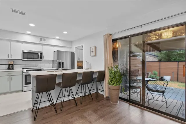 a kitchen with stainless steel appliances granite countertop a stove a refrigerator a kitchen island with chairs and wooden floor