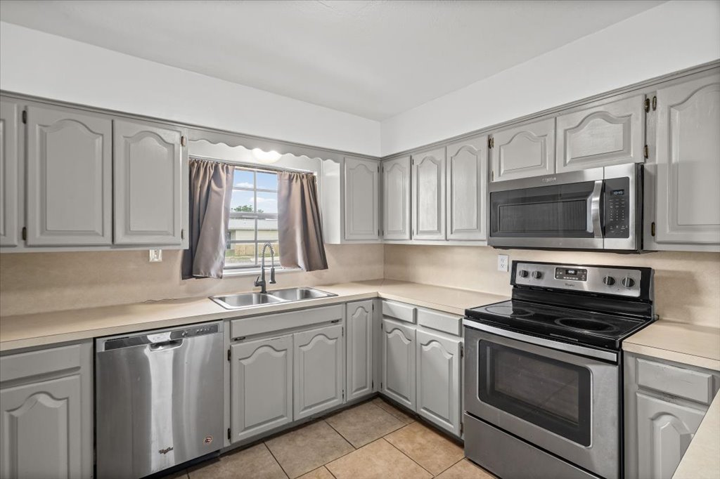 650 West Austin Street Luling, TX 78648 - Photo 6 of 18 This galley kitchen features a suite of stainless steel appliances, ample cabinetry, and practical tile flooring.