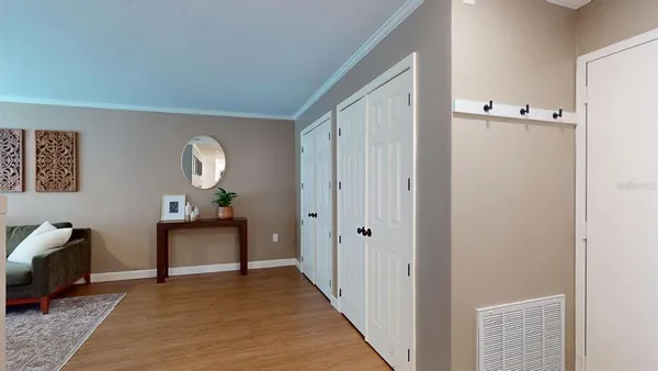 a view of a livingroom from a hallway with wooden floor and furniture