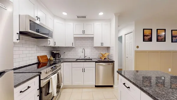 a kitchen with stainless steel appliances granite countertop a stove a sink and a refrigerator