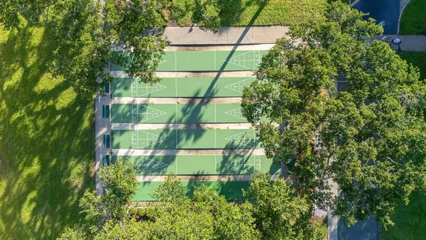 an aerial view of a residential apartment building with a yard and parking spaces