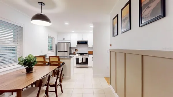 a kitchen with stainless steel appliances a dining table chairs and a refrigerator