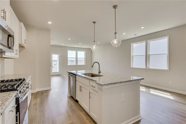 a kitchen with stainless steel appliances granite countertop a sink stove and wooden floor